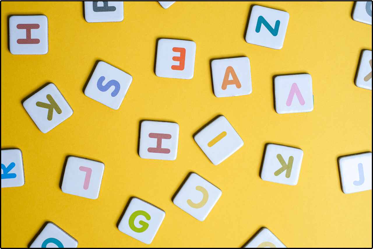 Educational alphabet blocks with various letters on a yellow surface.